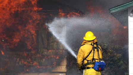 A Reno firefighter tries to save an outbuilding as a house burns in a 400-acre brush fire in south Reno, Nev., on Friday, Nov. 18, 2011. The fire raged through more than 400 acres, claimed at least one life, injured several others, destroyed dozens of homes and blanketed Reno and its suburban enclaves in a fiery curtain as violent winds sidelined firefighters and rescue helicopters. (AP Photo/Cathleen Allison)