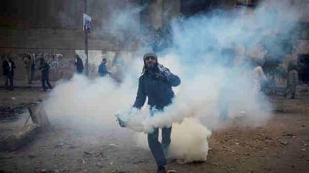 A protester throws a tear gas canister away near the interior ministry during clashes with the Egyptian riot police, not seen, in downtown Cairo, Egypt, Sunday, Nov. 20, 2011. Firing tear gas and rubber bullets, Egyptian riot police on Sunday clashed for a second day with thousands of rock-throwing protesters demanding that the ruling military quickly announce a date to hand over power to an elected government.