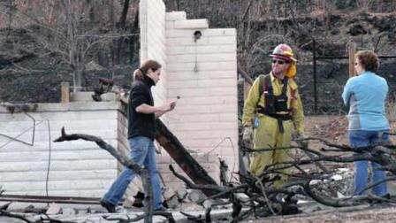 Austin Hardage, 23, left, returns, Saturday, Nov. 19, 2011 to the charred rubble that used to be the home where he and his wife, Sarah Hardage, 22, lived in an upscale community in the Sierra foothills in southwest Reno, Nev. before a wildfire destroyed that home and 31 others early Friday.