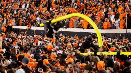 A fan hangs from a goal post after it was torn down in celebration of Oklahoma States 44-10 win over Oklahoma in an NCAA college football game in Stillwater, Okla., Saturday, Dec. 3, 2011. (AP Photo/Sue Ogrocki)