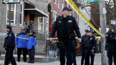 Police officers stand near a crime scene where a police officer was shot in the Cypress Hills section of the Brooklyn borough of New York, Monday, Dec. 12, 2011. Officials say the officer later died after he was shot in the face while responding to a break-in at a Brooklyn apartment.