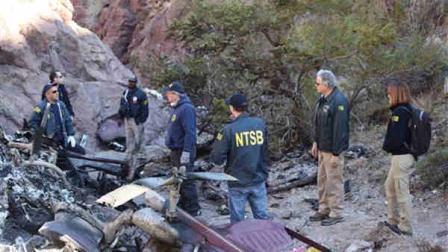 In this photo provided by the National Transportation Safety Board on Saturday, Dec. 10, 2011, investigators examine the wreckage of a sightseeing tour helicopter from Las Vegas that crashed in the Lake Mead National Recreation Area in Nevada near the Hoover Dam. The Wednesday, Dec. 7, 2011 crash killed the pilot and four tourists, including a couple from Kansas and a couple from New Delhi, India.