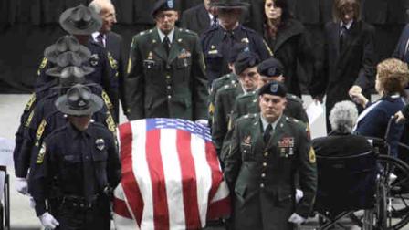The casket of Virginia Tech police officer Deriek W. Crouse is carried out of a funeral service at Cassell Coliseum on the campus of Virginia Tech in Blacksburg, Va., Monday, Dec. 12, 2011. Crouses wife, Tina, center right, follows the casket.