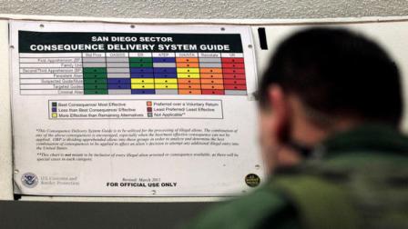 A Border Patrol agent works in front of a color-coded chart at a detention center Wednesday, Jan. 11, 2012, in Imperial Beach, Calif. The Border Patrol is moving to end its revolving-door policy of turning migrants around to Mexico without any punishment in what amounted to an invitation to immediately try their luck again.