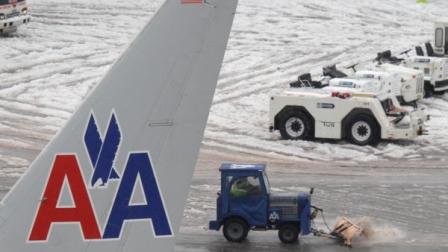 A plow clears the tarmac near an American Airlines plane at Seattle-Tacoma International Airport, Thursday, Jan. 19, 2012, in Seattle. On the heels of heavy snow that fell Wednesday, the Western Washington region was hit with an ice storm Thursday that closed runways at the airport and stranded hundreds of travelers. (AP Photo/Ted S. Warren)