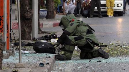 A Thai Explosive Ordnance Disposal (EOD) official examines a backpack that was left on the bomb site by a suspected bomber in Bangkok, Thailand Tuesday, Feb. 14, 2012.