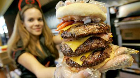 FILE - Courtney Chapman, a waitress dressed as a nurse at the Heart Attack Grill, holds up a triple bypass burger Friday, Dec. 1, 2006 in Tempe, Ariz. (AP Photo/Matt York)