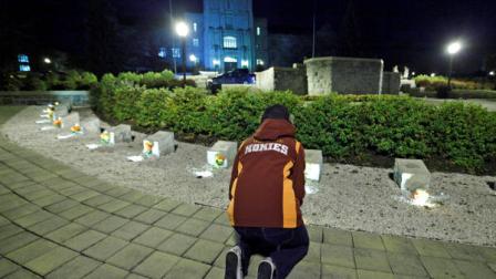 A student participates in an impromptu candlelight vigil in front of the 4/16 memorial on the campus of Virginia Tech after two shootings on the campus in Blacksburg, Va., Thursday, Dec. 8, 2011. A gunman killed a police officer and then apparently shot himself to death nearby in a baffling attack that shook up the campus nearly five years after it was the scene of the deadliest shooting rampage in modern U.S. history. (AP Photo/Steve Helber)