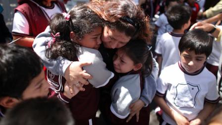 A woman comforts her children outside a school at the Roma neighborhood after a earthquake felt in Mexico City Tuesday March 20, 2012. A strong, long earthquake with epicenter in Guerrero state shook central southern Mexico on Tuesday, swaying buildings in Mexico City and sending frightened workers and residents into the streets..(AP Photo/Alexandre Meneghini)
