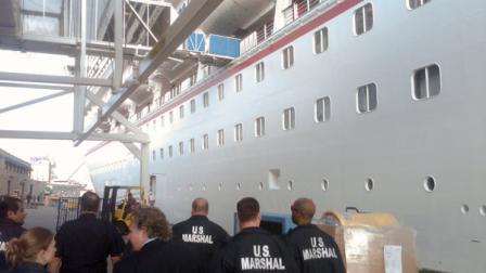 In this picture provided by the Eaves Law Firm on Saturday, March 31, 2012, unidentified US Marshals are seen approaching the Carnival Triumph cruise ship moored at Galveston harbor, TX, U.S.A., Saturday, March 31, 2012. An arrest warrant was issued on Friday for the MS Carnival Triumph, a 2,758-passenger cruise liner based in Galveston, that is owned by the same company that owns the Costa Concordia, the luxury cruise ship that ran aground off the coast of central Italy in January killing some 30 people. U.S. Magistrate Judge John Froeschner of Galveston ordered the ship held in a $10 million lawsuit filed by the family of a German tourist who died aboard the Costa Concordia shipwreck off the Italian coast. (AP Photo/Eaves Law Firm, handout)
