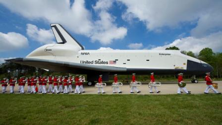 In this photo provided by NASA, the United States Marine Corp Drum and Bugle Corps and Color Guard march by the Space Shuttle Enterprise at the Steven F. Udvar-Hazy Center Thursday, April 19, 2012 in Chantilly, Va. Enterprise was the first space shuttle orbiter, built for NASA to perform test flights in the atmosphere and was not capable of spaceflight. It has been on display at the Udvar-Hazy Centers Space Hangar since 2004. Enterprise will be transferred to the Intrepid Sea, Air and Space Museum in New York City.