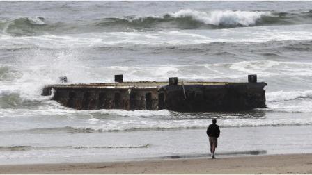 A man looks at the massive dock with Japanese lettering that washed ashore on Agate Beach Wednesday, June 6, 2012, in Newport, Ore. (AP Photo/Rick Bowmer)