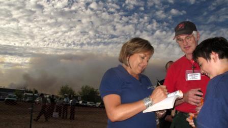New Mexico Gov. Susana Martinez signs a new testament for Frankie Pirelli, left, as Firefighters for Christ volunteer. Bill McGeachy watches at the Little Bear Fire incident command area Monday June 11, 2012 in Ruidoso, N.M. Hundreds of residents have been evacuated in this resort town due to the Little Bear wild land fire. (AP Photo/Juan Carlos Llorca)