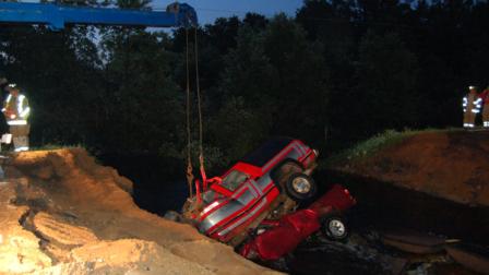 In a photo provided by the Clark County Sheriffs Department, Clark County Sheriffs deputies watch Thursday, June 20, 2012 as two vehicles are extracted from a washout hole after they crashed in to the large hole created by heavy rains, killing three people, on county road M near Neillsville, Wis. Clark County Chief Deputy Jim Backus says a passer-by discovered the two vehicles early Thursday. Authorities say a pickup truck carrying two people crashed into the hole, then another vehicle with one occupant crashed into the same hole. All three were pronounced dead at the scene. (AP Photo/Clark County Sheriffs Department)