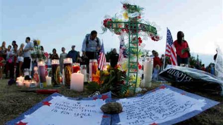 A written message that begins To all the innocent souls... this is for you, is shown near a display of candles, flags, and other tributes, Friday, July 20, 2012, in Aurora, Colo., across the street from the movie theater where a gunman killed at least 12 people and wounded dozens of others Friday in one of the deadliest mass shootings in recent U.S. history. (AP Photo/Ted S. Warren)