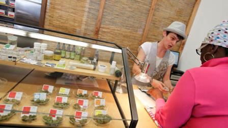 Harborside Health Center sales associate Jess Bradley helps customer Cindy Smith, right, with a marijuana purchase at the center on Thursday, July 12, 2012 in Oakland, Calif. (AP Photo/Aric Crabb, Bay Area News Group)