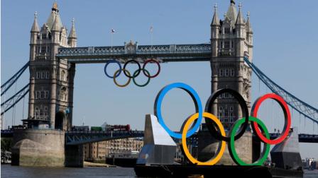 Olympic Rings hang from the Tower Bridge beyond a set of rings floating on the River Thames Thursday, July 26, 2012, in London.