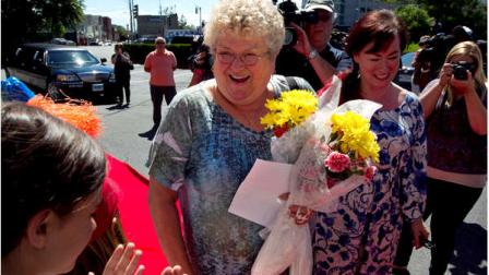 Bus monitor Karen Klein, of Greece, N.Y., holds flowers as she is welcomed to an award ceremony in her honor at a radio station, in Boston on Thursday, June 28, 2012. A viral video of Klein being bullied by four middle schoolers shows the 68-year-old school bus monitor trying her best to ignore the stream of profanity, insults and outright threats directed at her aboard a bus in New York state. (AP Photo/Steven Senne)