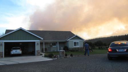 A Washington State Patrolman approaches a home near Cle Elum, Wash. to notify residents its time to evacuate on Wednesday, Aug. 15, 2012. A wildfire there has forced the evacuation of hundreds of residents and destroyed dozens of homes. (AP Photo/Shannon Dininny)