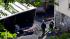 Officials walk past a car that was destroyed by...