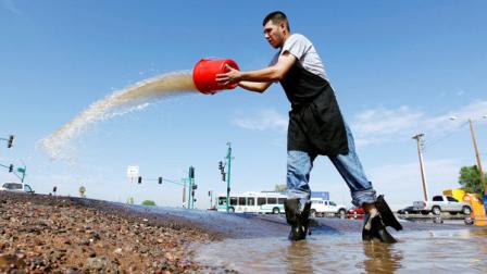 After a night of heavy storms, Jesus Navarro, of Phoenix, tries to remove water from a flooded parking lot Wednesday, Aug. 22, 2012, in Phoenix. More storms are expected in the metro area over the next two days.(AP Photo/Ross D. Franklin)