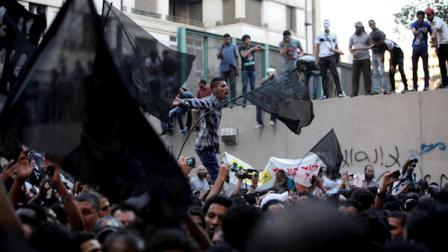Egyptian protesters climb the walls of the U.S. embassy while others chant anti U.S. slogans during a protest in Cairo, Egypt, Tuesday, Sept. 11, 2012. Egyptian protesters, largely ultra conservative Islamists, have climbed the walls of the U.S. embassy in Cairo, went into the courtyard and brought down the flag, replacing it with a black flag with Islamic inscription, in protest of a film deemed offensive of Islam. Arabic graffiti reads Their is only one God. (AP Photo/Nasser Nasser)