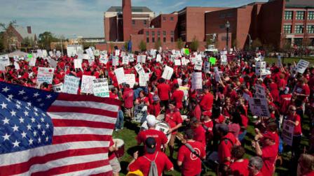 A large group of public school teachers marches past John Marshall Metropolitan High School on Wednesday, Sept. 12, 2012 in West Chicago. Teachers walked off the job Monday for the first time in 25 years over issues that include pay raises, classroom conditions, job security and teacher evaluations. (AP Photo/Sitthixay Ditthavong)