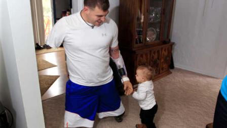 Army Staff Sgt. Travis Mills plays with his daughter Chloe in his boyhood home in Vassar, Mich., Thursday, Oct. 4, 2012. Mills is visiting his hometown for the first time since losing all four limbs while fighting in Afghanistan. Mills, his wife, Kelsey, and their 1-year-old daughter, Chloe, will be the grand marshals of Vassar High Schools homecoming parade on Thursday evening. (AP Photo/Carlos Osorio)