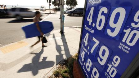 A boogie boarder walks past a sign displaying high gas prices in Laguna Beach, Calif. Friday, Oct. 5, 2012. In many areas in California, gas prices have jumped 40 cents in a week as refinery problems have created shortages and helped send wholesale prices soaring. (AP Photo/Chris Carlson)