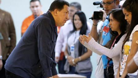 Venezuelas President Hugo Chavez, left, speaks with an electoral worker at a polling station before casting his ballot for the presidential election in Caracas, Venezuela, Sunday, Oct. 7, 2012. Chavez is running for re-election against opposition candidate Henrique Capriles. (AP Photo/Fernando Llano)