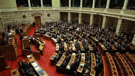 Greeces Prime Minister Antonis Samaras delivers a speech from the podium, left, during a parliament meeting for vote on 2013 countrys budget in Athens, Sunday, Nov. 11, 2012. The vote by lawmakers on the 2013 budget which would once more cut pensions and salaries so Greece can qualify for its next vital batch of rescue loans. (AP Photo/Thanassis Stavrakis)