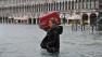 A tourist crosses flooded St. Marks Square in Venice, Italy, Sunday, Nov. 11, 2012. High tides have flooded Venice, leading Venetians and tourists to don high boots and use wooden walkways to cross St. Marks Square and other areas under water. Flooding is common this time of year and Sundays level that reached a peak of 58.66 inches (149 centimeters) was below the 63 inches (160 centimeters) recorded four years ago in the worst flooding in decades. (AP Photo/Luigi Costantini) 