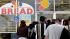 Customers wait in line to buy products at the...