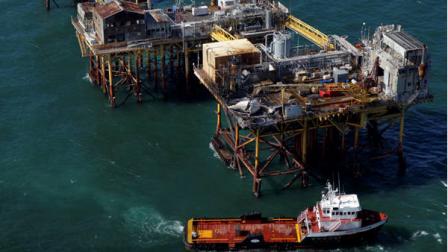 In this aerial photograph, a supply vessel moves near an oil rig damaged by an explosion and fire, Friday, Nov. 16, 2012, in the Gulf of Mexico about 25 miles southeast of Grand Isle, La. Four people were transported to a hospital with critical burns and two were missing. (AP Photo/Gerald Herbert)
