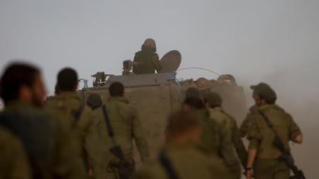 Israeli soldiers march behind an armored personnel carrier in a gathering area near the Israel Gaza Strip border, in southern Israel, Sunday, Nov. 18, 2012. President Barack Obama on Sunday defended Israels airstrikes on the Gaza Strip, but he warned that escalating the offensive with Israeli ground troops could deepen the death toll and undermine any hope of a peace process with the Palestinians. (AP Photo/Ariel Schalit)