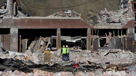 Inspectors stand in debris, Saturday, Nov. 24, 2012, at the site of a gas explosion that leveled a strip club in Springfield, Mass., on Friday evening. Investigators were trying to figure out what caused the blast where the multistory brick building housing Scores Gentlemans Club once stood. (AP Photo/Jessica Hill)