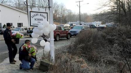 A couple of volunteer firefighters place flowers at a makeshift memorial at a sign for the Sandy Hook Elementary school, Saturday, Dec. 15, 2012 in Sandy Hook village of Newtown, Conn. The massacre of 26 children and adults at Sandy Hook Elementary school elicited horror and soul-searching around the world even as it raised more basic questions about why the gunman, 20-year-old Adam Lanza, would have been driven to such a crime and how he chose his victims. (AP Photo/Mary Altaffer)