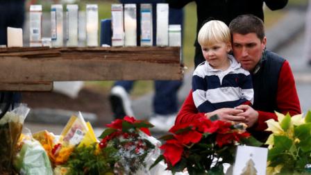 A man holds a child while paying respects to shooting victims at a makeshift memorial outside of St. Rose of Lima Roman Catholic Church, Sunday, Dec. 16, 2012, in Newtown, Conn. On Friday, a gunman killed his mother at their home and then opened fire inside the Sandy Hook Elementary School in Newtown, killing 26 people, including 20 children.(AP Photo/Julio Cortez)