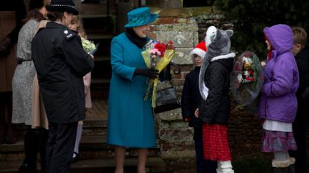 Britains Queen Elizabeth II, center, smiles as she receives flowers from children after attending the British royal familys traditional Christmas Day church service in Sandringham, England, Tuesday, Dec. 25, 2012.
