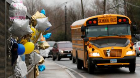 FILE - In this Dec. 18, 2012 file photo, a school bus rolls toward a memorial in Newtown, Conn., for victims of the Sandy Hook Elementary School shooting. Nearly three weeks after the shooting rampage, classes are starting Thursday, Jan. 3, 2013 for the Sandy Hook students at a repurposed school in the neighboring town of Monroe, where the students desks have been taken along with backpacks and other belongings that were left behind in the chaos following the shooting on Dec. 14. (AP Photo/Charles Krupa, File)