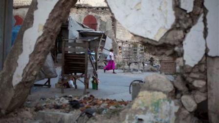 A woman walks past buildings damaged by the 2010 earthquake in downtown Port-au-Prince, Haiti, Wednesday, Jan. 9, 2013. Governments around the world have spent about half of the $5.3 billion pledged for Haitian reconstruction. Most of the rubble is gone; there are two new sewage treatment plants north of the capital and a few homes. Many Haitians had expected more progress by now. (AP Photo/Dieu Nalio Chery)