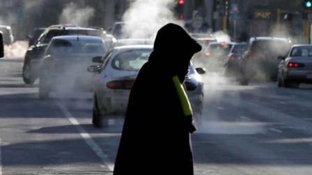 Steam from cars exhaust rises as a woman dressed for the weather crosses a street Tuesday, Jan. 22, 2013 in downtown Minneapolis where temperatures were in the double-digit, sub-zero numbers. (AP Photo/Jim Mone)