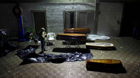 A man stands around coffins containing the remains of victims after the bodies were identified at a gymnasium in Santa Maria city, Rio Grande do Sul state, Brazil, Sunday, Jan. 27, 2013. A fast-moving fire roared through the crowded, windowless Kiss nightclub in southern Brazil early Sunday, within seconds filling the space with flames and a thick, toxic smoke that killed more than 230 panicked partygoers who gasped for breath and fought in a stampede to escape.(AP Photo/Felipe Dana)