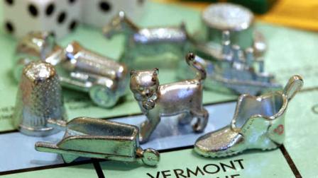 The newest Monopoly token, a cat, center, rests on a Boardwalk deed next to other tokens still in use including the wheelbarrow, left, and the shoe, right, at Hasbro Inc. headquarters, in Pawtucket, R.I., Tuesday, Feb. 5, 2013. Voting on Facebook determined that the cat would replace the iron token. (AP Photo/Steven Senne)