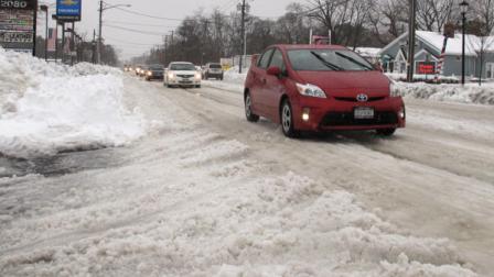 Vehicles try to maneuver across snow and ice-covered state Route 112 in Medford, N.Y., Monday, Feb. 11, 2013. While major highways on eastern Long Island were beginning to recover from a weekend blizzard, many local roads remained covered in snow and ice two days after the storm. (AP Photo/Frank Eltman)