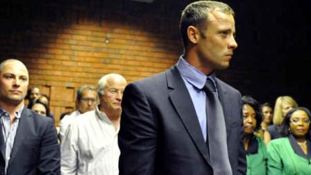Olympian Oscar Pistorius, foreground, stands following his bail hearing, as his brother Carl, left, and father Henke, second from left, look on in Pretoria, South Africa, Tuesday, Feb. 19, 2013. Pistorius fired into the door of a small bathroom where his girlfriend was cowering after a shouting match on Valentines Day, hitting her three times, a South African prosecutor said Tuesday as he charged the sports icon with premeditated murder. The magistrate ruled that Pistorius faces the harshest bail requirements available in South African law. He did not elaborate before a break was called in the session. (AP Photo)