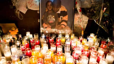 Memorial candles stand beside a picture of Kimani Kiki Gray during a vigil for the deceased teen in the East Flatbush neighborhood of Brooklyn, Wednesday, March 13, 2013, in New York. The 16-year-old was shot to death on a Brooklyn street last Saturday night by plainclothes police officers who claim the youth pointed a .38-caliber revolver at them. (AP Photo/John Minchillo)