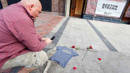Joe Burke, of Haverhill, Mass., places a t-shirt at the spot where the first bomb detonated near the finish line of the Boston Marathon on Boylston Street in Boston, Wednesday, April 24, 2013. (AP Photo/Michael Dwyer)