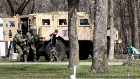 This May 3, 2013, photo provided by Jeremy Jones shows authorities with Buford Rogers, right, during a raid on a mobile home in Montevideo, Minn. Authorities said Monday, May 6, that Rogers was arrested, charged with one count of being a felon in possession of a firearm, and that the agency believes is disrupted a potential terror attack after a search of the home turned up Molotov cocktails, suspected pipe bombs and firearms. (AP Photo/Montevideo American-News, Jeremy Jones)
