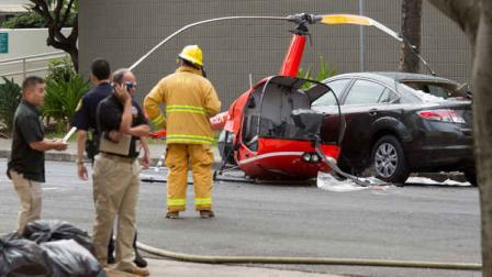 The wreckage of a small helicopter that crashed sits next to a car in downtown Honolulu Wednesday, May 8, 2013. The helicopter crashed near the intersection of Fort Street and Beretania Street. The condition of the pilot is unknown. (AP Photo/Eugene Tanner)